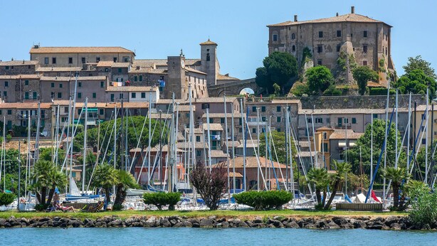 A coastal town with historic buildings, a prominent tower, and a marina with numerous boats. - Lovely home in Farnese (Farnese)