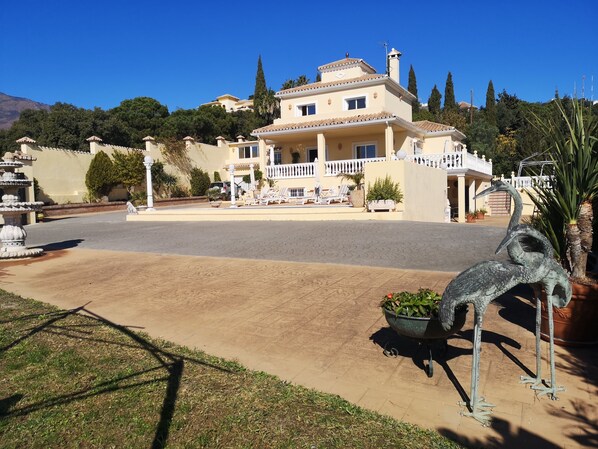 Un edificio grande de dos pisos, con un amplio camino de entrada y una fuente decorativa.