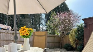 A patio with a table, chairs, a large umbrella, and a vase of flowers. - 3 bedroom accommodation in Upper Soudley (Upper Soudley)