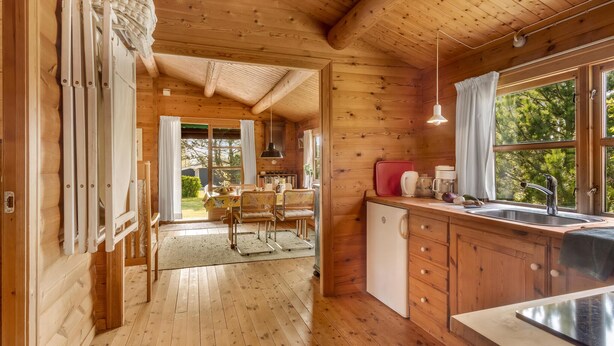 L'intérieur d'une cabane en bois comprend un coin repas, une cuisine et de grandes fenêtres.