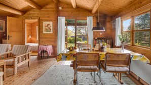 Une chaleureuse cabane en bois dotée d’un coin repas avec une table dressée pour quatre personnes, entourée de chaises en osier.