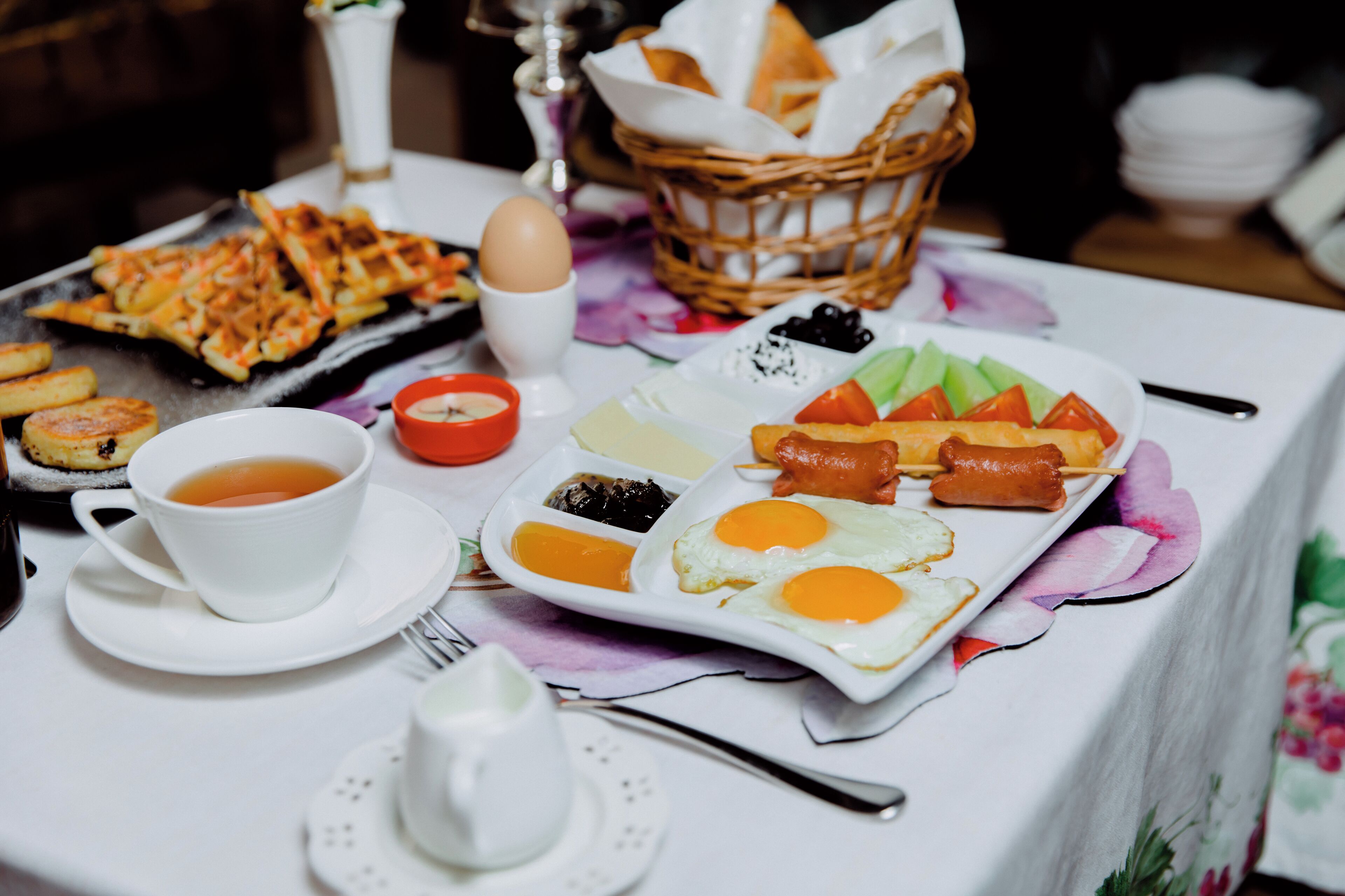 A breakfast table with various dishes including eggs, sausages, and toast.