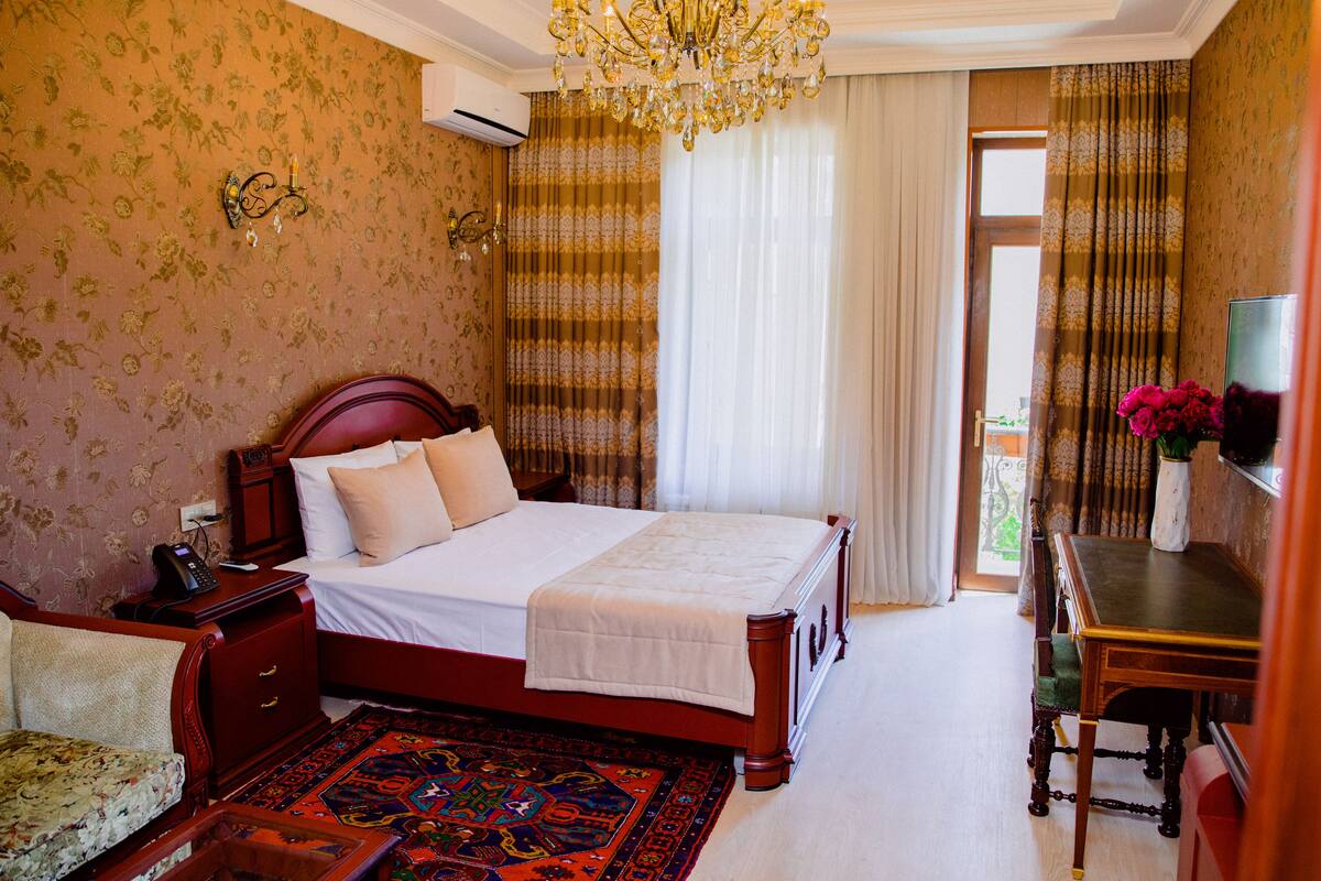 A bedroom with a large bed, a desk, and a chair.