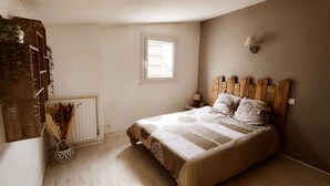 Un dormitorio con cabecera de madera, una ventana, un radiador y una lámpara de noche.