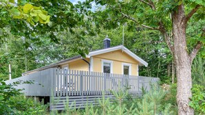 Une petite cabane en bois dotée d’un porche grillagé, entourée d’une végétation luxuriante.