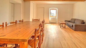 A spacious room with a wooden dining table, chairs, a sofa, and a small table.