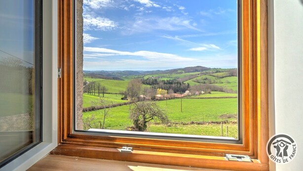 A window with a view of green fields and hills.