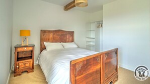 A bedroom with a wooden bed, a bedside table with a lamp, and a wardrobe.