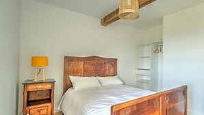 A bedroom with a wooden bed, a bedside table with a lamp, and a wardrobe. - Majoa - Villecheneve (VILLECHENEVE)