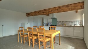A spacious kitchen with a wooden dining table and chairs, white cabinets, and a tiled backsplash. - Majoa - Villecheneve (VILLECHENEVE)
