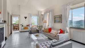 A spacious living room with a sofa, coffee table, and a view of the city through large windows. - 3 bedroom gorgeous home in Rapallo (Rapallo)