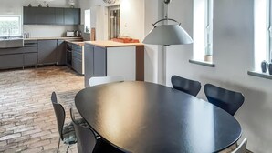 Uma cozinha moderna com armários escuros, bancada de madeira e uma área de jantar com mesa e cadeiras redondas.