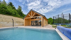 Eine Holzhütte mit Pool, umgeben von einem Zaun und Bäumen.