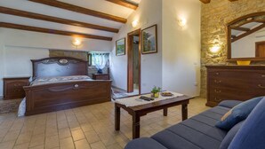 Un dormitorio con una cama de madera, una mesita de noche, un aparador, un sofá y una pared de piedra.