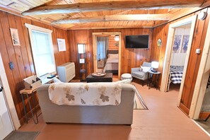 Ein gemütliches Wohnmobil-Interieur mit einer Sitzecke, einem kleinen Tisch, einem Fernseher und einem Bett.