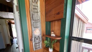 Ein Holzinterieur mit einem 'WELCOME'-Schild, einem kleinen Regal mit einer Pflanze und einem Laternen.