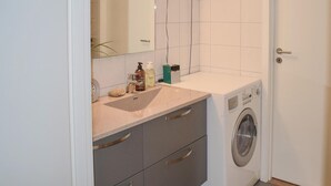 Une petite salle de bain comprenant un lavabo, un miroir et un lave-linge.