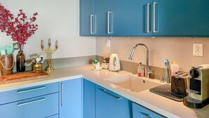 Une cuisine moderne avec des meubles bleus, un évier, une machine à café et divers ustensiles de cuisine disposés sur le plan de travail.