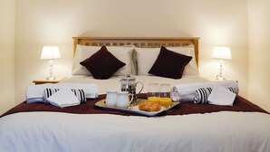 A neatly made bed with a tray of breakfast items, including croissants, juice, and coffee, in a hotel room. - 2 bedroom accommodation in Tregaron, near Lampeter (Tregaron, near Lampeter)