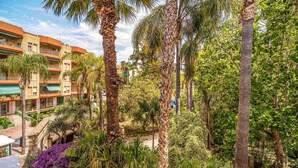 A hotel with multiple floors, balconies, and lush greenery including palm trees and purple flowers. - Nice apartment in Almuñécar with WiFi (Almuñécar)