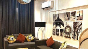 A modern living room with a sofa set, a coffee table, a rug, and a chandelier. - Luxor Apartments (Asaba)