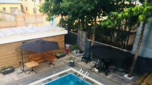 A swimming pool with a wooden deck and a bench. - Luxor Apartments (Asaba)