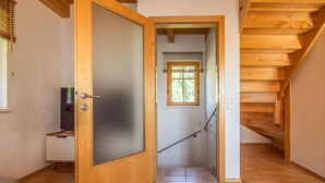 A wooden staircase leading to an upper floor, a door with a frosted glass panel, and a window with blinds.