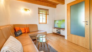 A living room with a sofa, a glass coffee table, a television, and a wooden door.