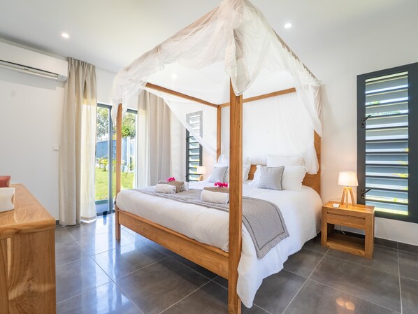 Une chambre moderne avec un lit à baldaquin, une table de chevet en bois et une vue sur l’extérieur.