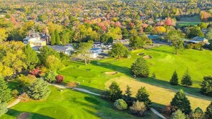 Campo de golf con club house, rodeado de árboles y zonas residenciales.