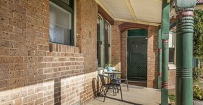 Traditional building with a brick facade and a green door, featuring a small outdoor seating area.