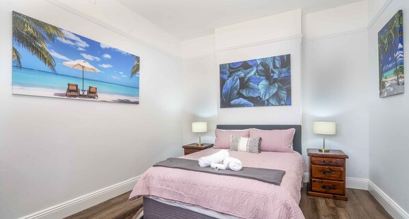Cozy bedroom with a large bed, two nightstands, and two framed artworks.