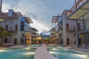 Un hotel moderno con piscina central, varios balcones y un diseño arquitectónico contemporáneo.