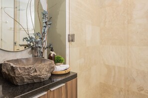 Un baño con un lavabo de piedra grande, armarios de madera y un espejo.