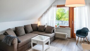 A modern living room with a brown sofa, a white coffee table, a black chair, and a large window with curtains. - Lovely apartment in Hasselberg with WiFi (Hasselberg)