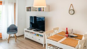 A modern living room with a flat-screen TV, white furniture, a bookshelf, and a wall clock. - Lovely apartment in Hasselberg with WiFi (Hasselberg)