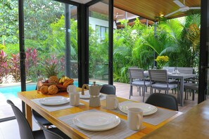 An outdoor dining area with a view of a pool and lush greenery.