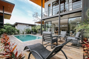 Une maison moderne dotée d’une piscine, de mobilier d’extérieur et d’un balcon.