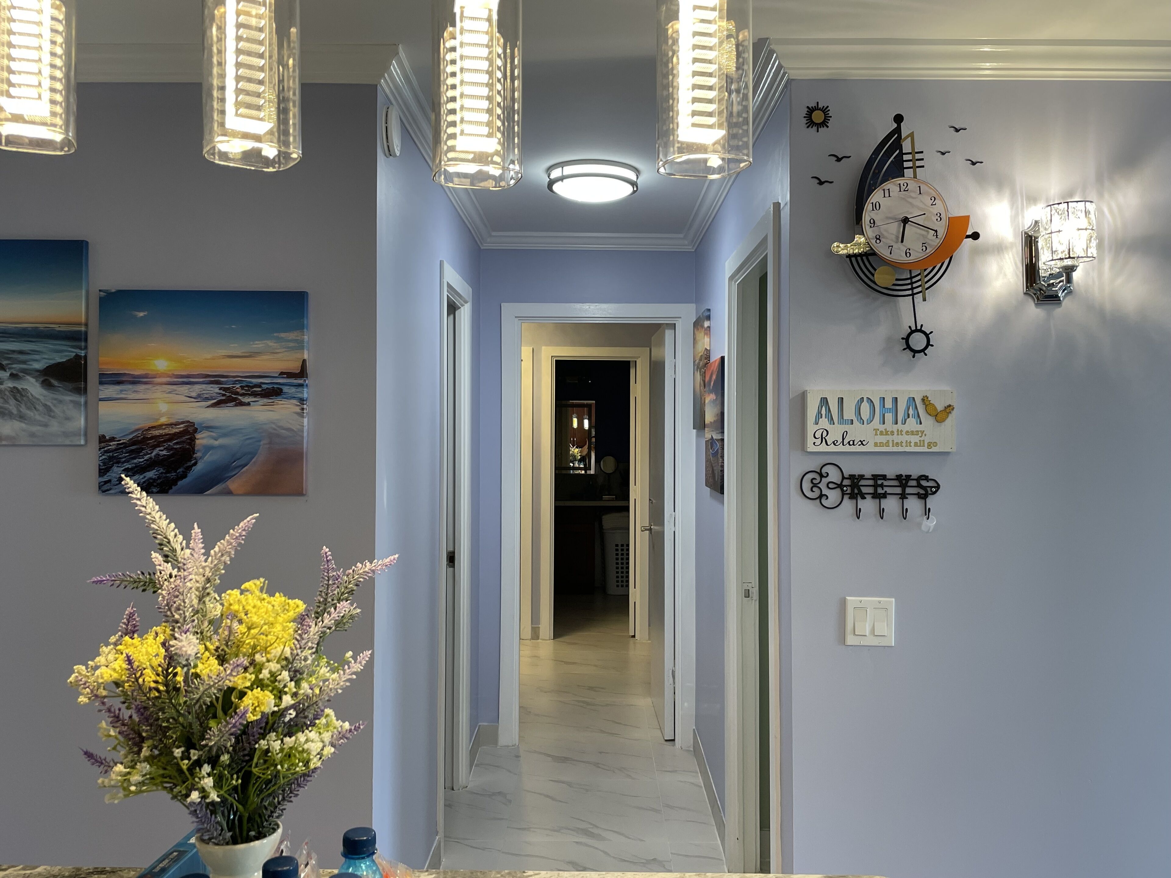 A hallway with a view into a room, a clock, and a wall with motivational phrases.