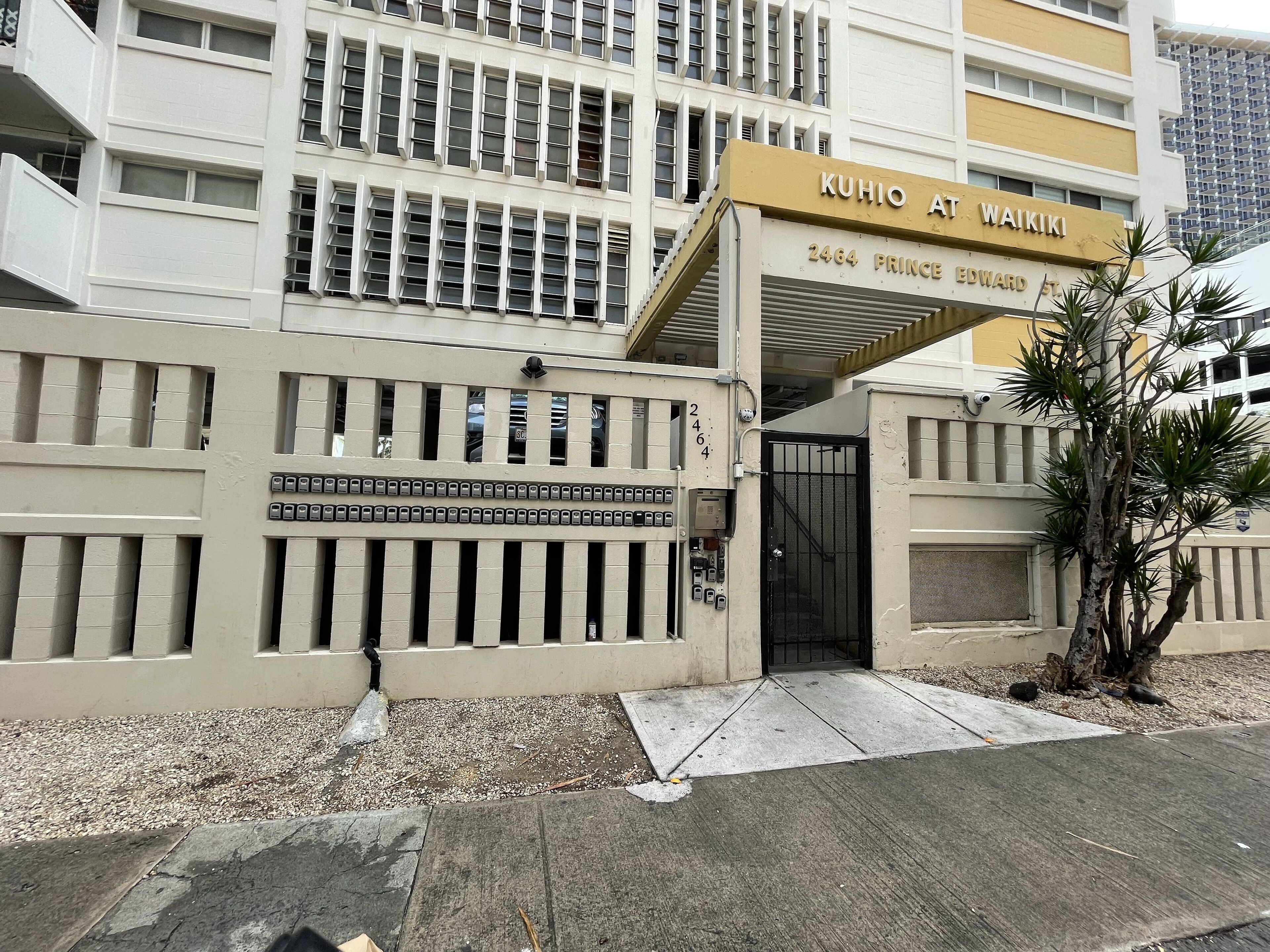 L'ingresso di un hotel con un cartello che riporta 'KUHIO AT WAIKIKI' e l'indirizzo '2464 PRINCE EDWARD ST'.