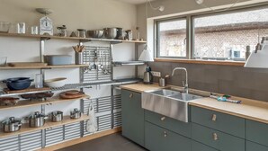Een moderne keuken met roestvrijstalen apparatuur, houten planken en een groot raam.