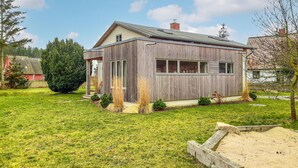 Een houten huis met schuin dak, schoorsteen en klein terras.