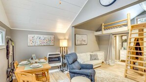 Una habitación acogedora con una cama litera, una mesa de comedor con sillas, un sofá y una lámpara.