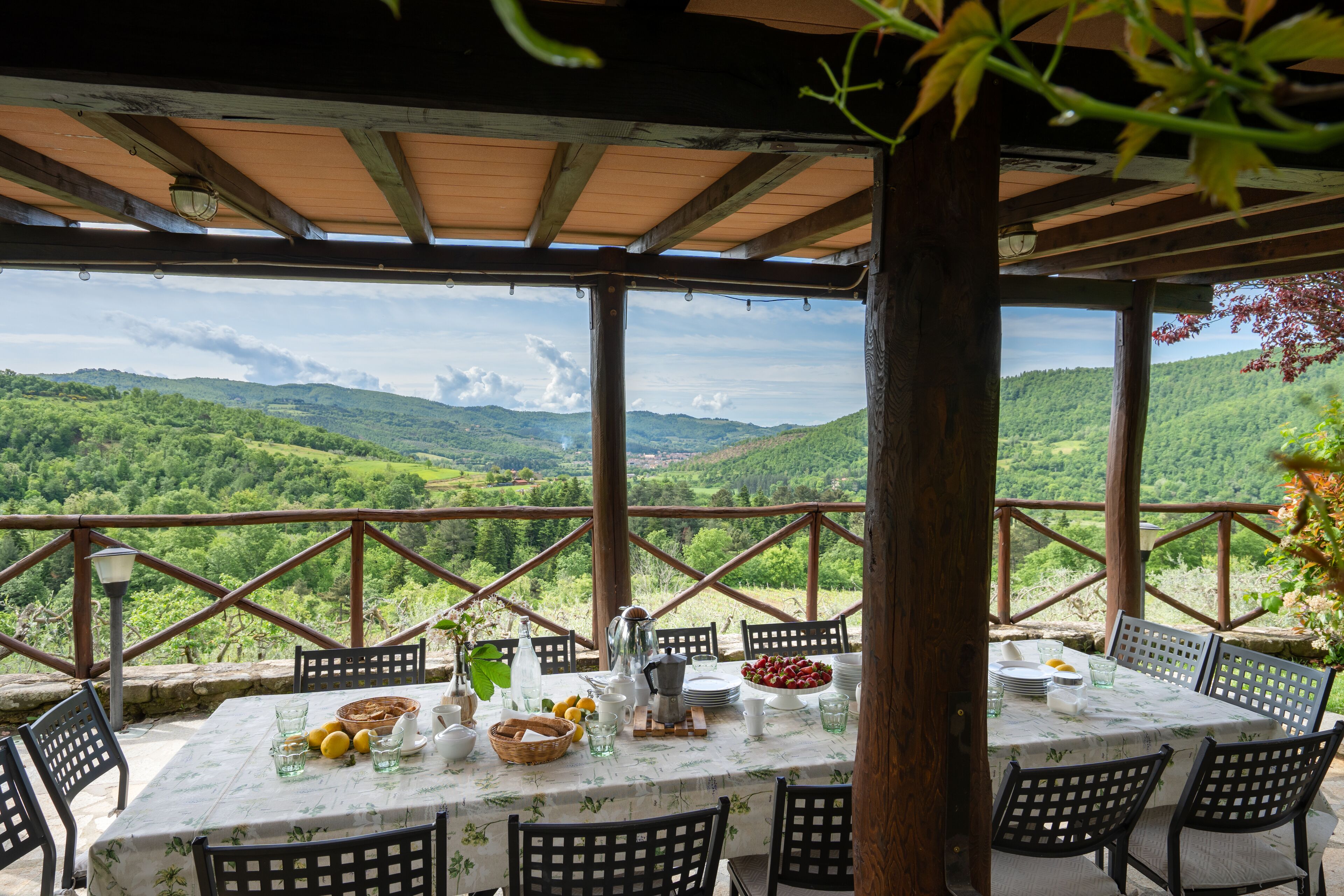 An outdoor dining area with a table set for four, overlooking a mountainous landscape.