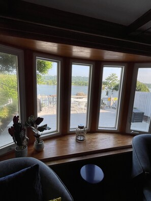 A room with a large window overlooking a dock and water, a small table, and two potted plants. - Gallipolis along the river. No cleaning fee and no Taxes. (Gallipolis)
