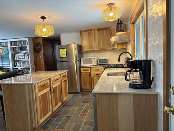 Une cuisine moderne avec des meubles en bois, un réfrigérateur en acier inoxydable, un four à micro-ondes, une cuisinière et une machine à café.