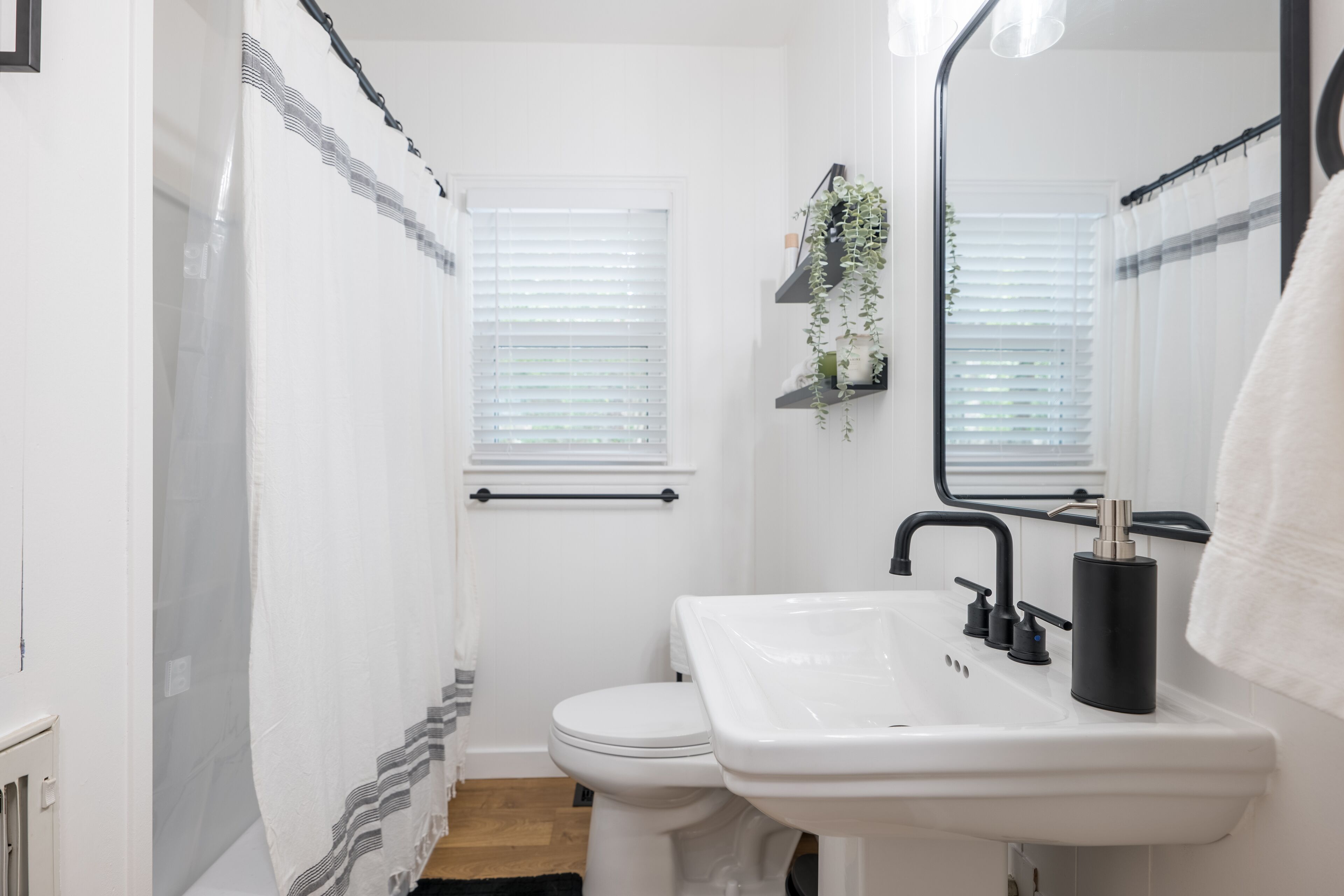 A bathroom with a white sink, black faucet, and a mirror.