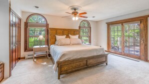 Ein Schlafzimmer mit einem hölzernen Bett, einem Deckenventilator und großen Fenstern.