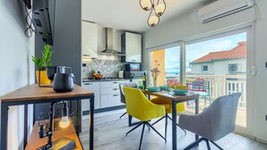 A modern kitchen with a dining area, large windows, and a balcony with outdoor furniture. - Brand new design apartment with big terrace (Kaštel Štafilić)