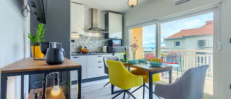 A modern kitchen with a dining area, large windows, and a balcony with outdoor furniture.